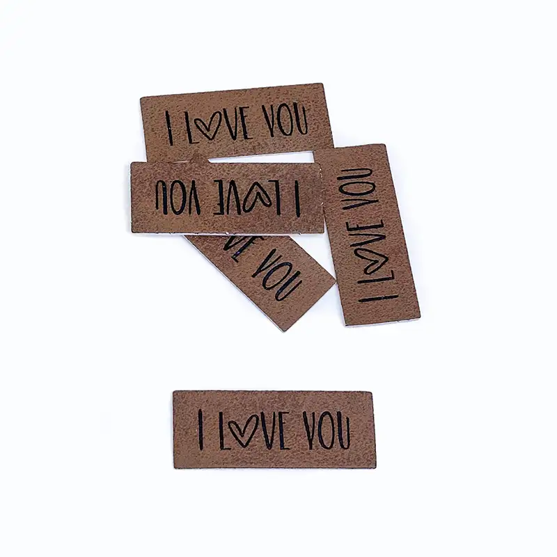 braune Lederlabels mit schwarzer Aufschrift " I Love you" das o wird in Form eines Herzens geschrieben