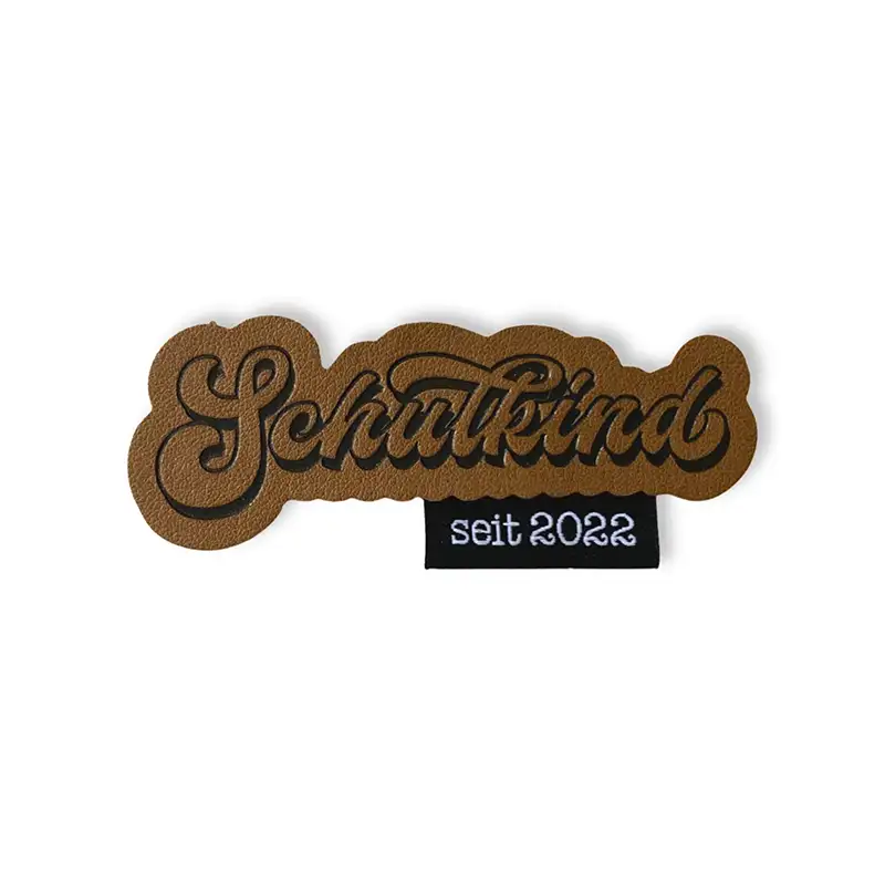 Lederlabel im Retrolook und dem Schriftzug Schulkind. schwarzes Weblabel mit der Aufschrift seit 2022